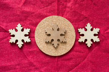 christmas themed background with wooden snowflake shapes and cork coaster on red felt