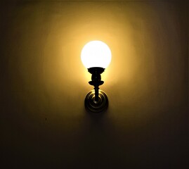 Lighted wall lamp in a dark room. Lights on. Concept background. Copy space.