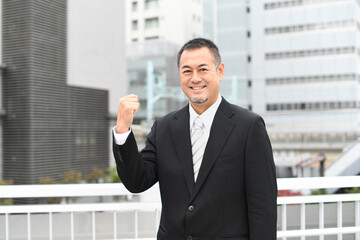 Fototapeta premium ガッツポーズをするスーツを着たミドルのビジネスマン