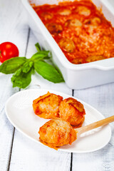 Meatballs with tomato and sour cream sauce on white plate. Close up