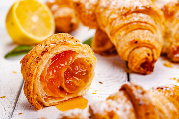 Croissants with lemon jam on white wooden background. Close up