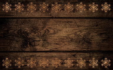 Christmas golden snowflakes on a dark wooden background of horizontal boards, sprinkled with golden twinkle powder, rustic style, table, top view
