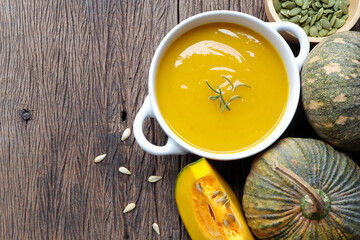Autumn pumpkin cream soup and pumpkins on the table. Seasonal autumn food.