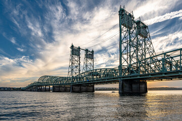 Transport arched truss drawbridge across the Columbia River against a cloudy sky at sunset
