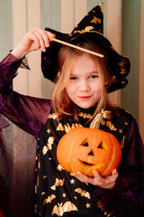 a little girl in a masquerade witch costume with a pumpkin lantern for Halloween