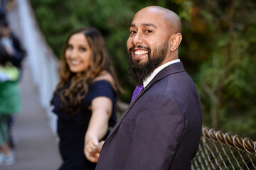 Full of love photo of an affectionate mixed race young couple holding each other on a suspension bridge at sunset
