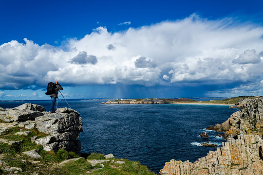 Professional nature photographer standing on a rock and taking photos of the breathtaking landscape of Brittany