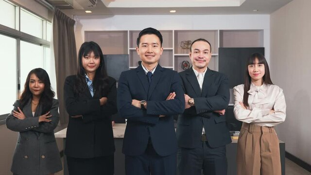 Successful group of business people smiling while standing with crossed arms in office, business team in formal suits they are folding their arms over the chest and looking at camera