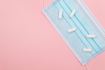 White Pills or Tablets on Medical Face Mask, Lying on Pink Background. Pharmaceutical Industry and Medicinal Products