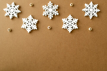 White wooden Snowflakes handmade on a Eco-frendly kraft paper background from above. Winter background  with Snowflakes Pattern, top view. Merry Christmas and New Year concept. Place for your text