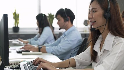 Call center young employee working with headset, Smiling customer support operator team at work surrounded by colleagues working in the office, Helpdesk customer services support agent concept