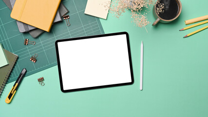 Above view digital tablet, coffee cup and stationery on green background.