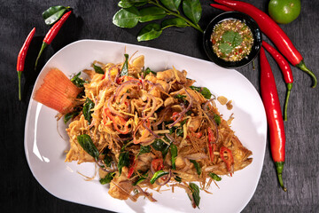 Thai fried fish with fish sauce and many herbs. A delicious recipe from Asia and spices ingredients for cooking on dark black wooden table background, Thai food, Asian foods, Thailand restaurant menu