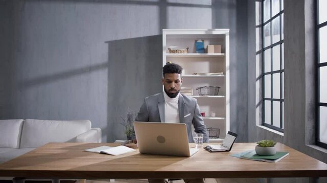 Young african american businessman strating work on laptop after break on sofa indoors in office