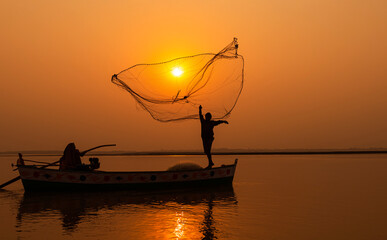 beautiful silhouette pictures  of  fisherman and a boat  with fishing net during sunset in golden...