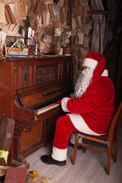 Santa Claus sits playing the piano grand piano for the new year and Christmas depicting music in a santa costume