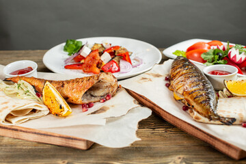 grilled mackerel and a salad of fresh vegetables. Serving on a wooden Board on a rustic table. Barbecue restaurant menu, a series of photos of different meats anf fish