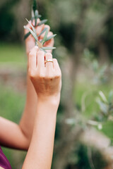 Fototapeta na wymiar Bride's hands are holding a green branch of a tree. Close-up