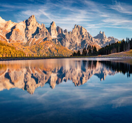 Fototapeta premium Pala di San Martino Mountain Range reflected in the surface of Malga Ces Lake. Superb autumn view of Dolomite Alps. Gorgeous outdoor scene of Italy, Europe. Beauty of nature concept background..