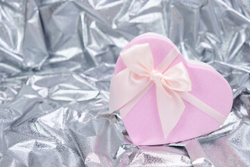 Crumpled gray foil and gift box. Reflective fanfold paper with pink ribbon box. Glitter paper for a gift.