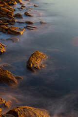 Fototapeta na wymiar Long exposure view of ocean water around the rock.