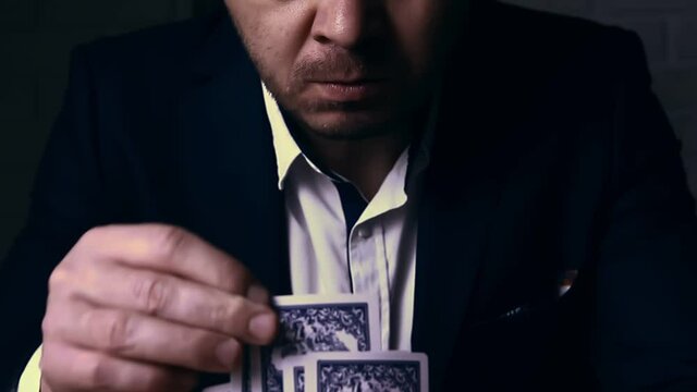 Young male wearing official  suit sitting of the poker table, game cards are everywhere. Gamer passion concept