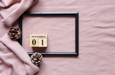 November1st., Cube wooden calendar showing date on 1 November, Wooden calendar on pink knitted sweater.