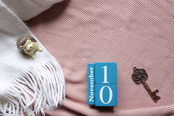 November 10th, Cube wooden calendar showing date on 10 November, Wooden calendar on pink knitted sweater.