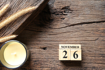 November 26th, Cube wooden calendar showing date on 26 November, Wooden calendar with date, candle and dry flowers on wooden table.