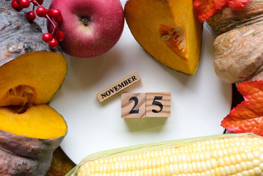 November 25th, Cube wooden calendar showing date on 25 November, Table decorated with Pumpkins ,Corn and Apple.Thanksgiving celebration traditional concept.