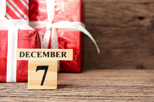 December 7th, Cube wooden calendar showing date on 7 December with red gift box on wooden table.