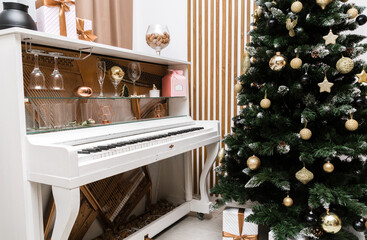 New Year decoration. Christmas tree near white piano in the classic interior