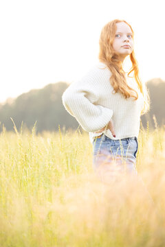 Fall fashion concept. Beautiful young woman in a cozy knitted sweater. Outdoor photo of funny hipster girl wearing trendy casual outfit. Warm light sunset. High quality photo