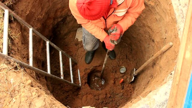 man digger inside the well with a large iron crowb