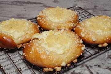 four buns with cheese lying on a metal rack standing on the kitchen counter