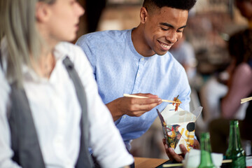 A young man is enjoying a meal during a lunch break in the office