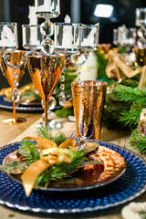 New Year's festive table setting. Merry Christmas family dinner by candlelight. Gold glasses for champagne. porcelain plates, candlesticks on the table close-up top view. christmas dinner table