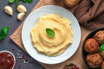Mashed potatoes in a white plate on a dark background.