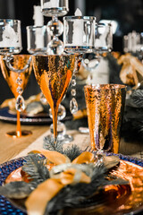 New Year's festive table setting. Merry Christmas family dinner by candlelight. Gold glasses for champagne. porcelain plates, candlesticks on the table close-up top view. christmas dinner table