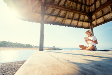 Relaxed and cheerful. Work and vacation. Outdoor portrait of happy young woman using tablet computer on terrace near the sea.