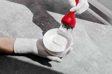 girl in white rubber protective gloves holding a brush in her hands and stirring hair dye close-up...