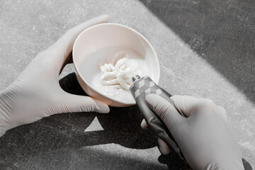 a girl in white protective gloves squeezes hair dye into an oxidizer. colorist at work close-up...