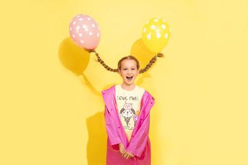 funny little pretty girl, 7 - 8 years old flies away on balloons tied to 2 pigtails. concept of magic, fantasy, humor, children's party. Positive emotions of surprise, joy, delight