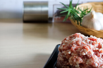 Raw fresh minced meat in a black plate with ingredients for making.
