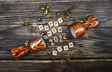 Banner. A symbol from the number 2022 with gold stars, sequins and a tiger-print firecracker on a wooden background. The concept of celebrating a Happy New Year and Christmas.