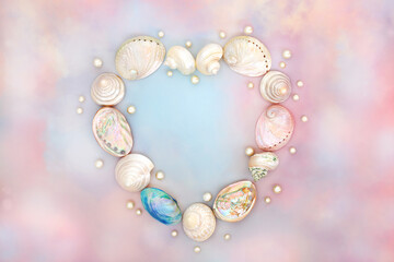 Heart shape  mother of pearl seashell wreath on rainbow coloured sky cloud background with pearls. Abstract love concept for Valentines Day, birthday, Mothers Day. Flat lay, top view, copy space.