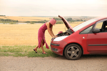 A frustrated girl with pink hair is standing with the hood of the car open