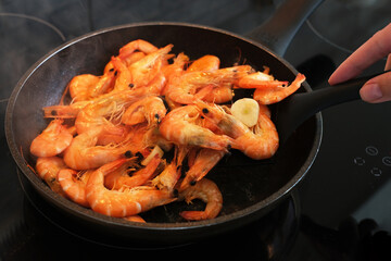 the cook fries shrimps in garlic sauce in a frying pan close-up. asian shrimp in sauce close-up