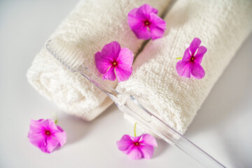 Obraz na płótnie Canvas Toothbrush and white towels, pink flowers aromatherapy. Oral care, body hygiene and morning daily routines.