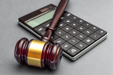 Judge gavel with calculator on grey background.